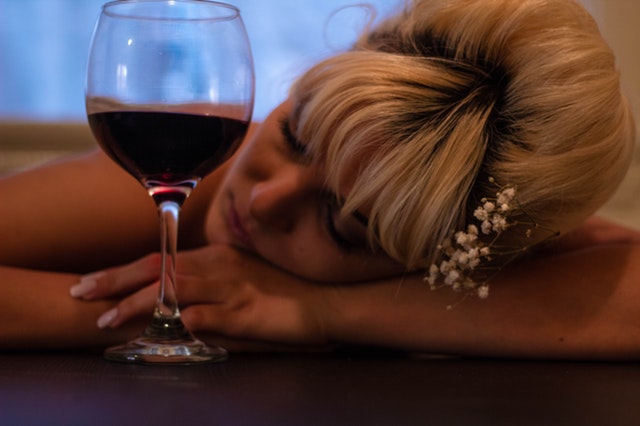 woman passed out holding glass of wine